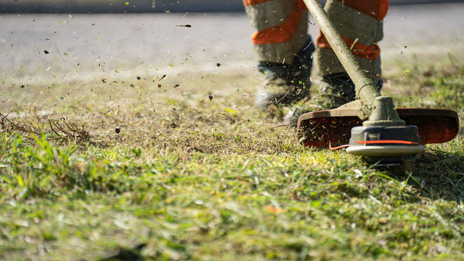 A man is trimming the grass with a lawnmower