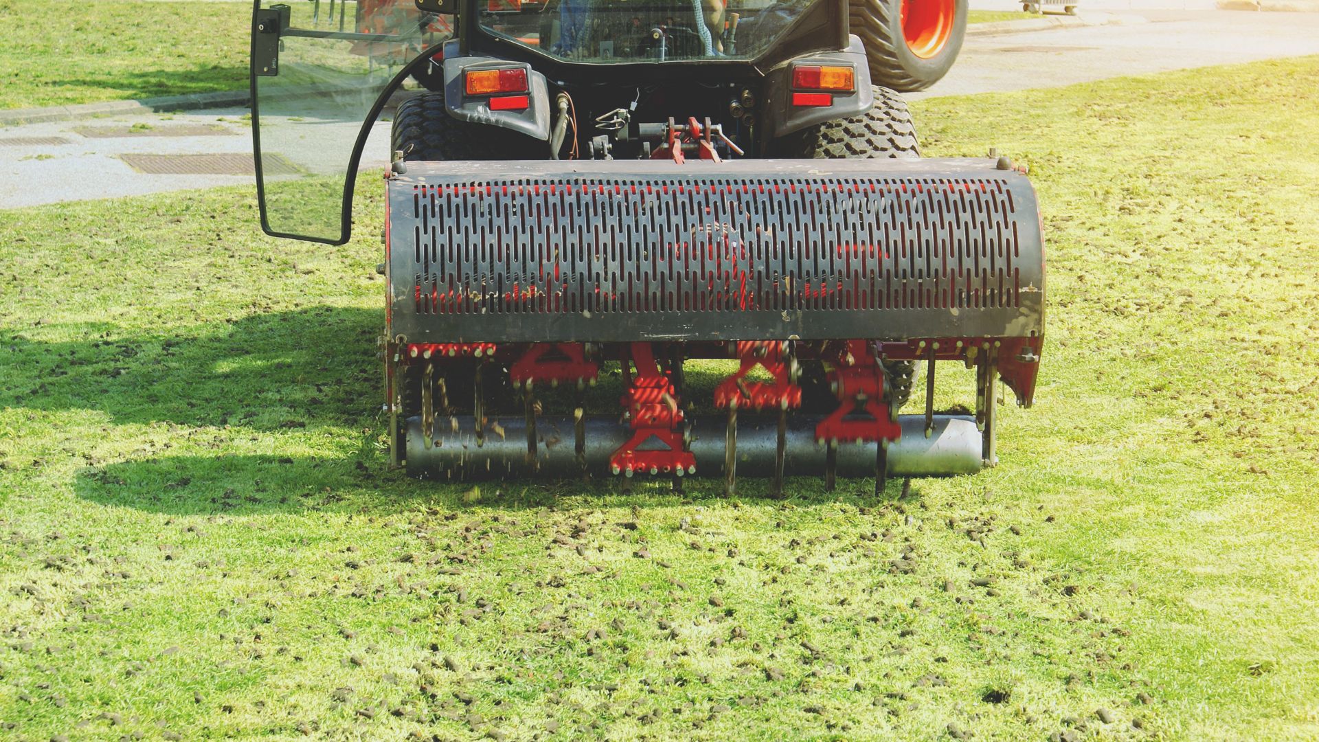 A tractor is parked in the grass with a raker attached to it
